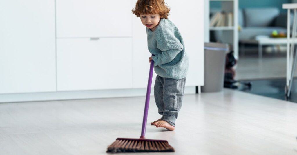 young boy sweeping floor, doing chores