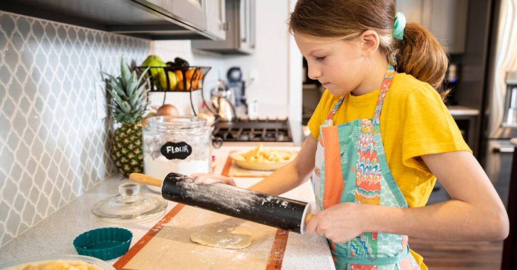 A young girl baking in a kitchen - cooking and baking are one of the ways how to make money as a kid