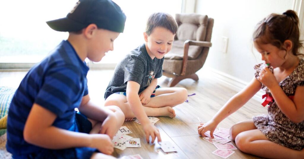 young kids playing cards on the floor
