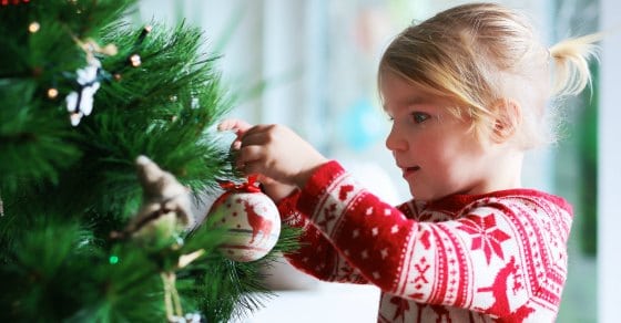 Little girl hanging ornaments on a Christmas tree 