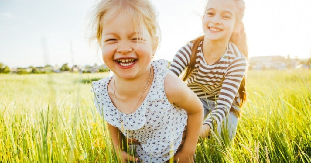 two sisters playing in a field doing summer activities for kids