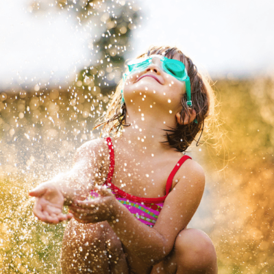 girl playing in a sprinkler
