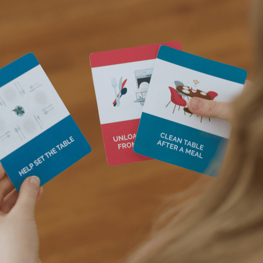Child's hand holding chore cards for kids