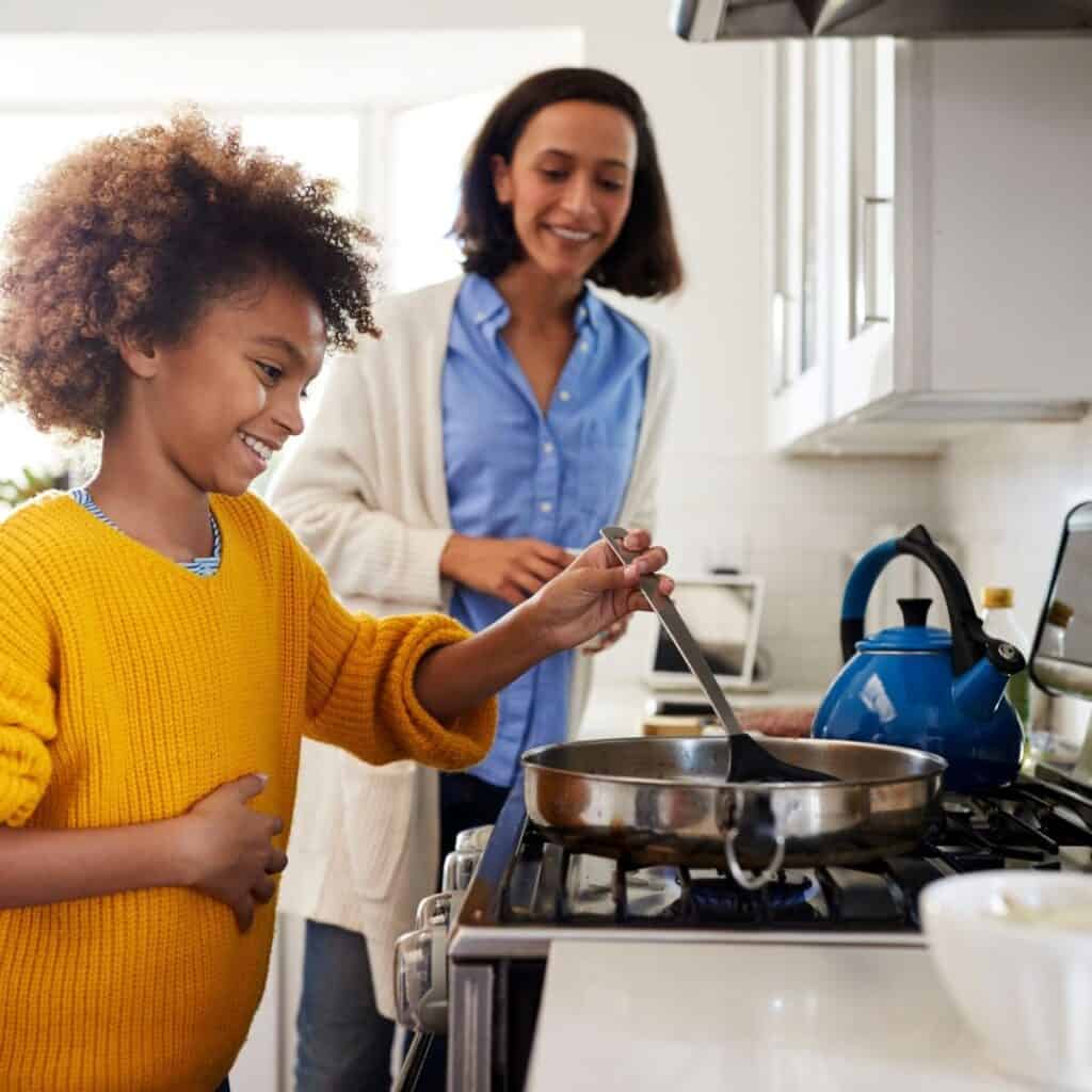 mother watching on as boy cooks on stove