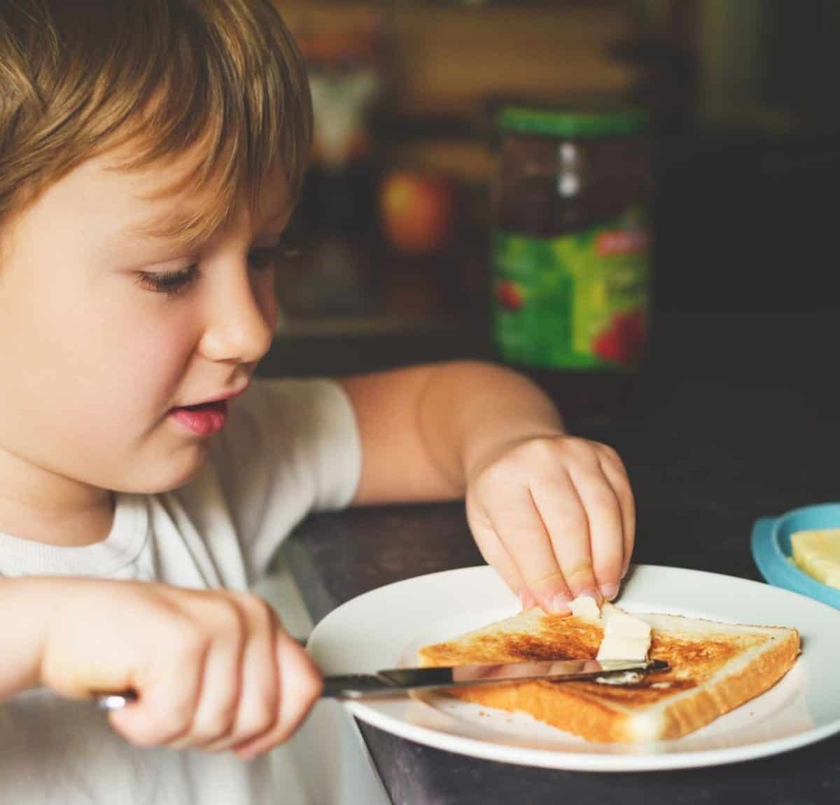 an independent child buttering toast on his own