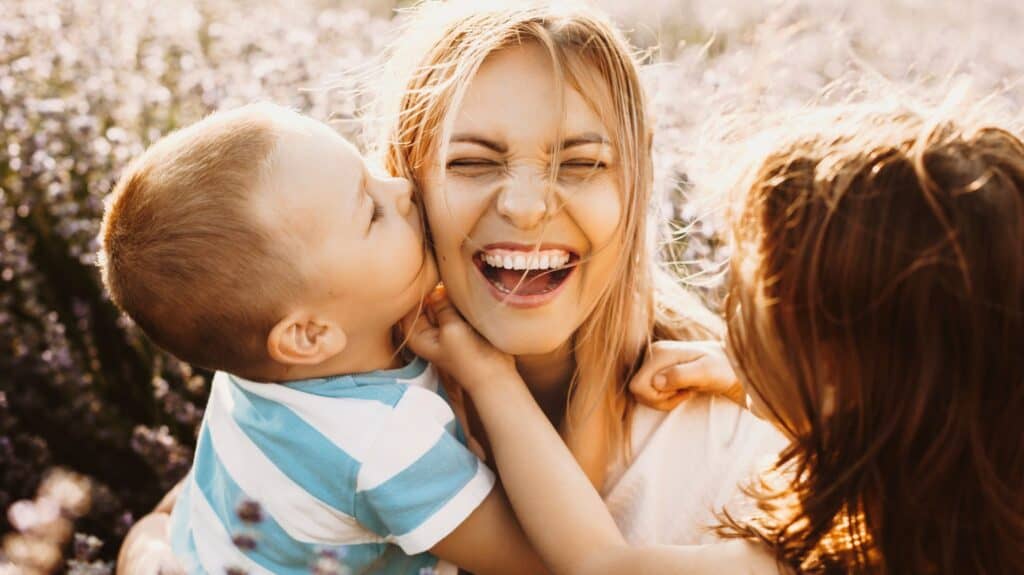 young son kissing mother on the cheek as daughter looks on