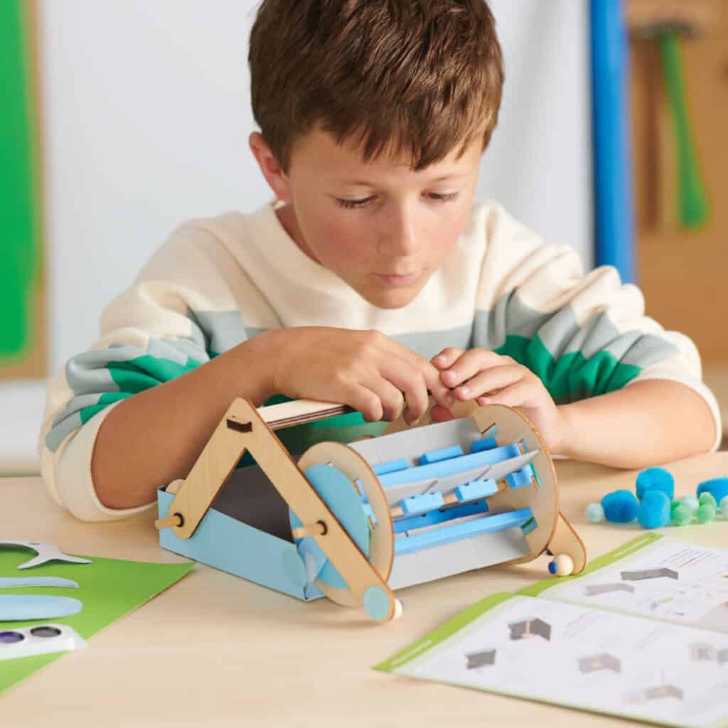 Мальчик собирает проект из коробки Kiwi Crate