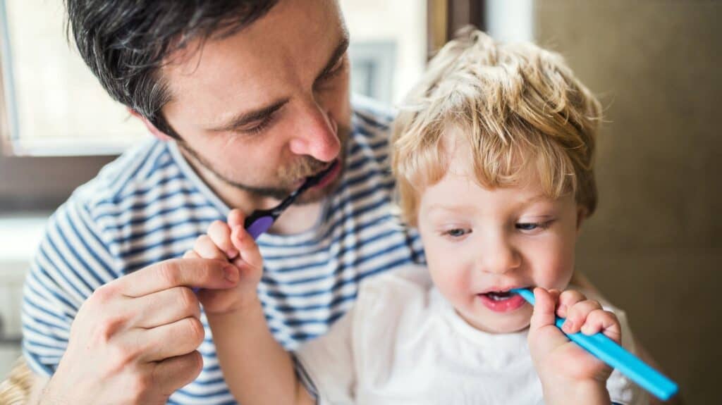 father and son brushing teeth together