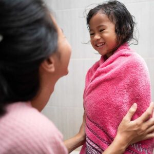 young girl getting dried off after taking a shower