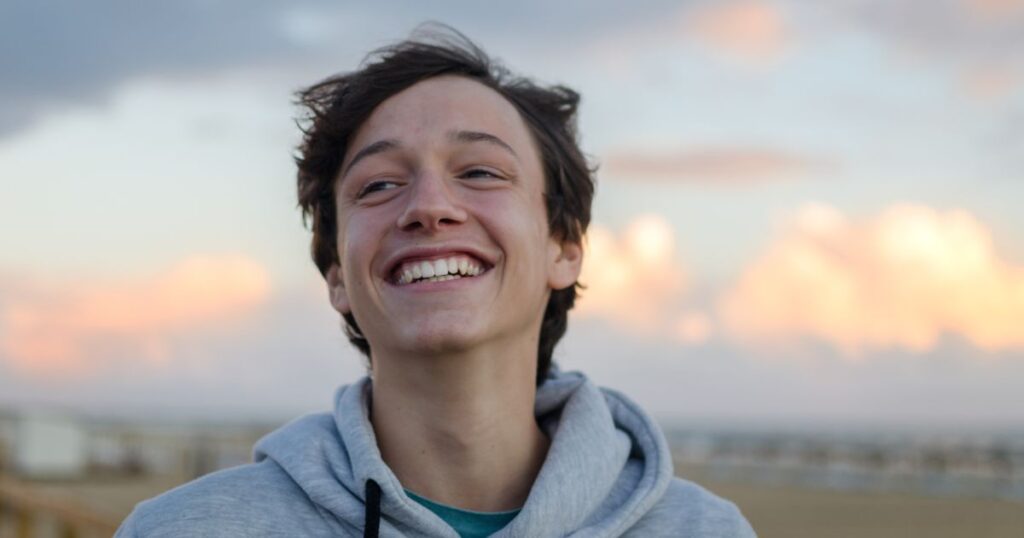 teenage boy smiling with beautiful sky in the background