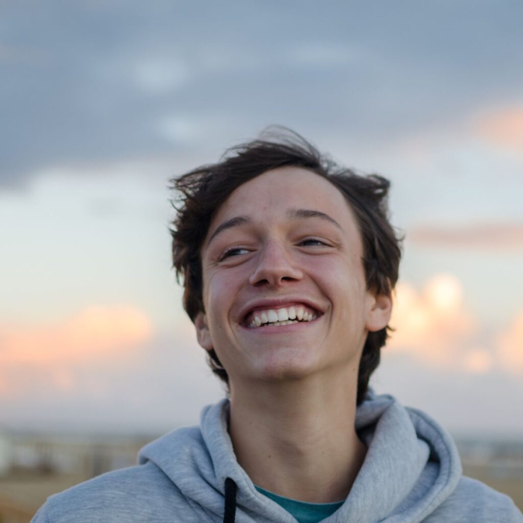 a teenage boy smiling with pretty sky in the background. house rules for teenagers don't have to be a battle