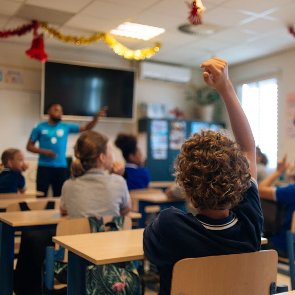 A boy raising his hand in a classroom