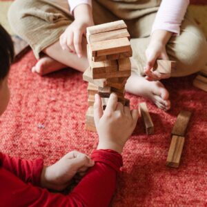 two children playing jenga on a red carpet